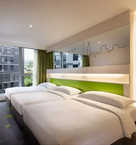 Three beds by the work desk in the Deluxe Triple Room.